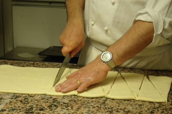 Croissant dough being sliced into triangles.