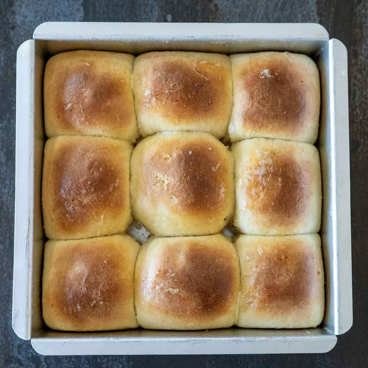 Golden brown brioche rolls in pan.