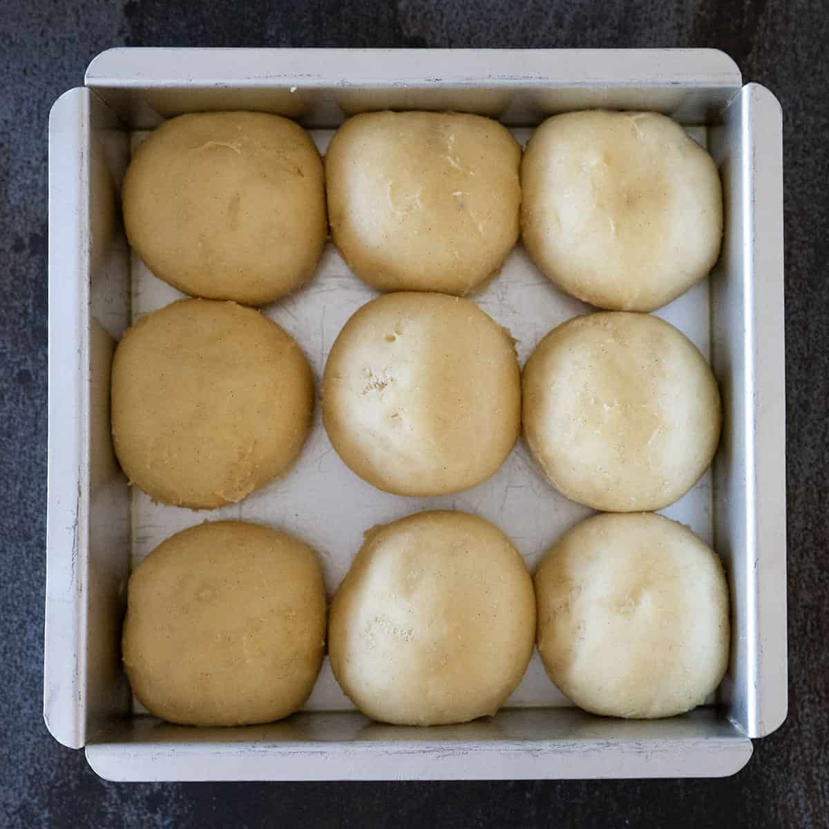 Brioche rolls rising in pan.