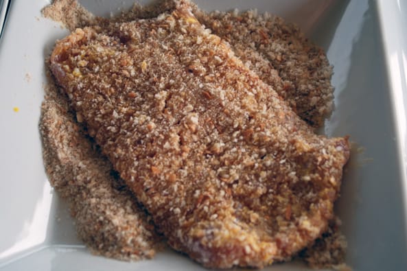 pork cutlet being dredged in breadcrumbs