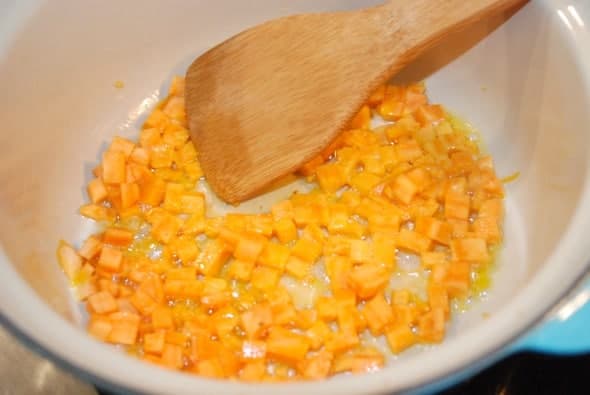 sweet potato sautéing in a pan with a wooden spoon