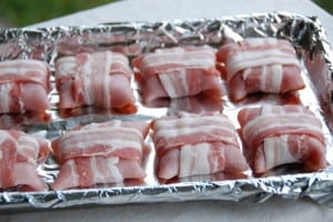 bacon wrapped around sausage and ham on pan.