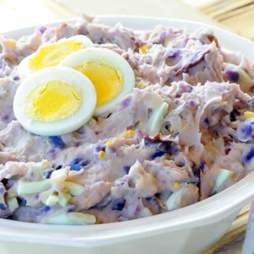 Bowl of purple potato salad with hard-boiled egg slices.