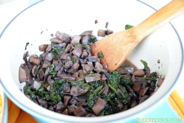 mushrooms and spinach simmering in a pan