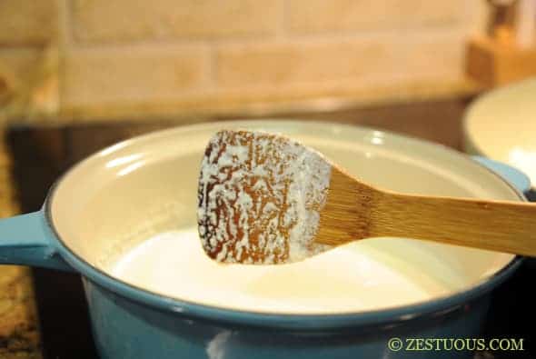milk boiling in a pot with a wooden spoon