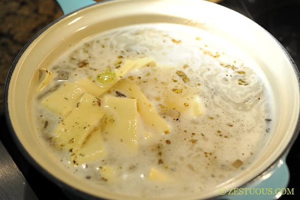 noodles being added to chicken noodle soup