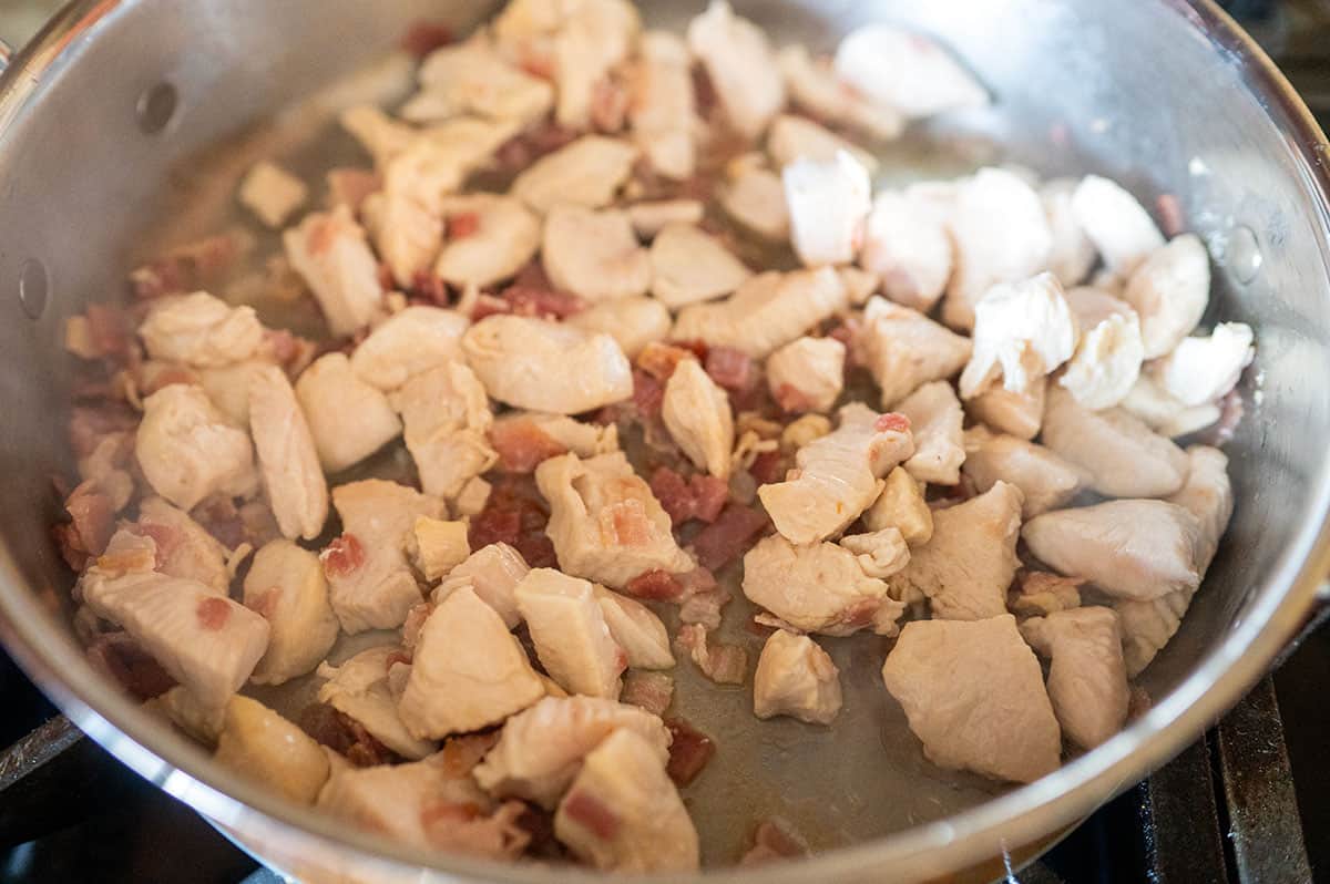 Chicken and bacon cooked in skillet.