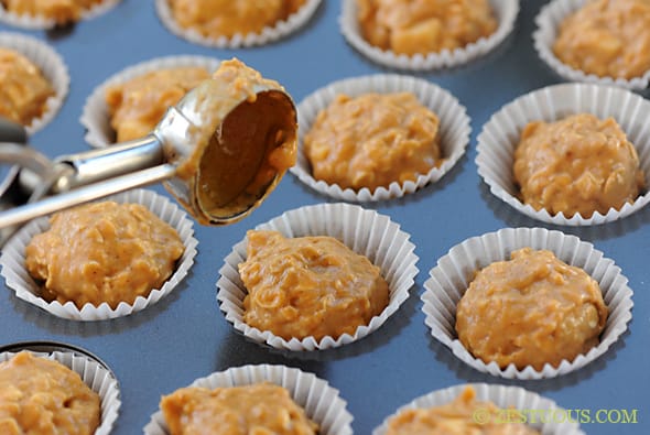 pumpkin muffin batter being placed in a muffin tin with an ice cream scoop