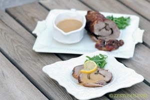 herb pork on plate with citrus herb sauce.