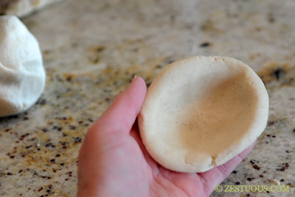 flattened pupusa dough with a dent in the middle