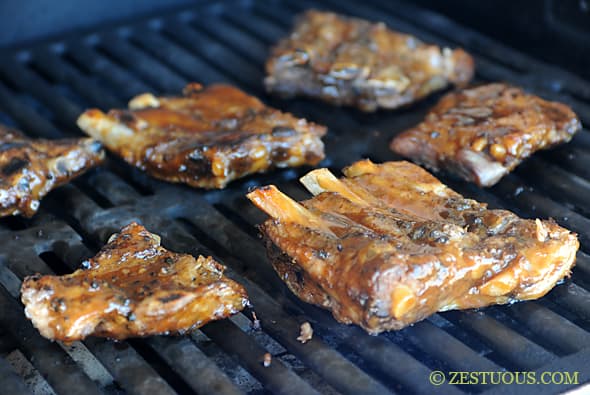 ribs on the grill with sauce on them