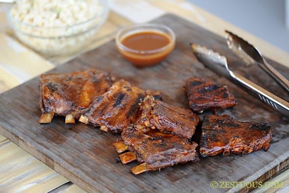 ribs with a side of sauce on a wooden cutting board