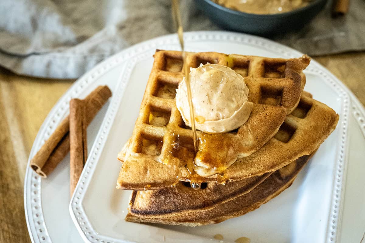 Pouring apple syrup on apple waffles.