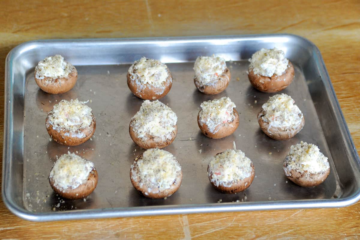 Mushrooms stuffed and placed on sheet pan before being baked.